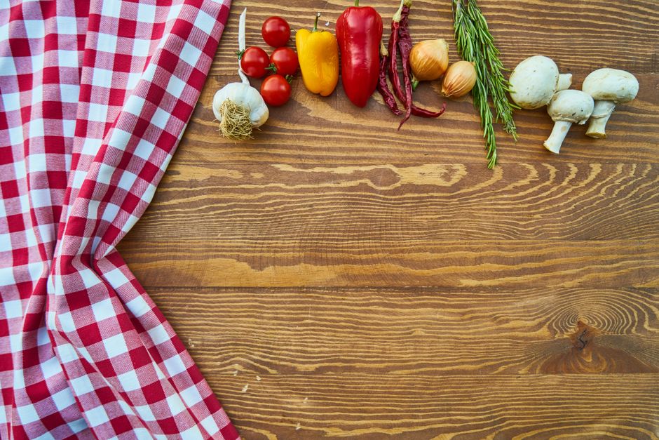 Fresh vegetables and herbs arranged on a wooden kitchen table
